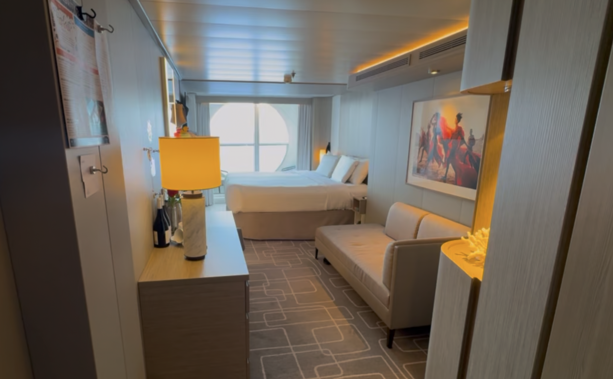 Interior of Celebrity Beyond cabin 7106, with the bed, seating area, and porthole veranda