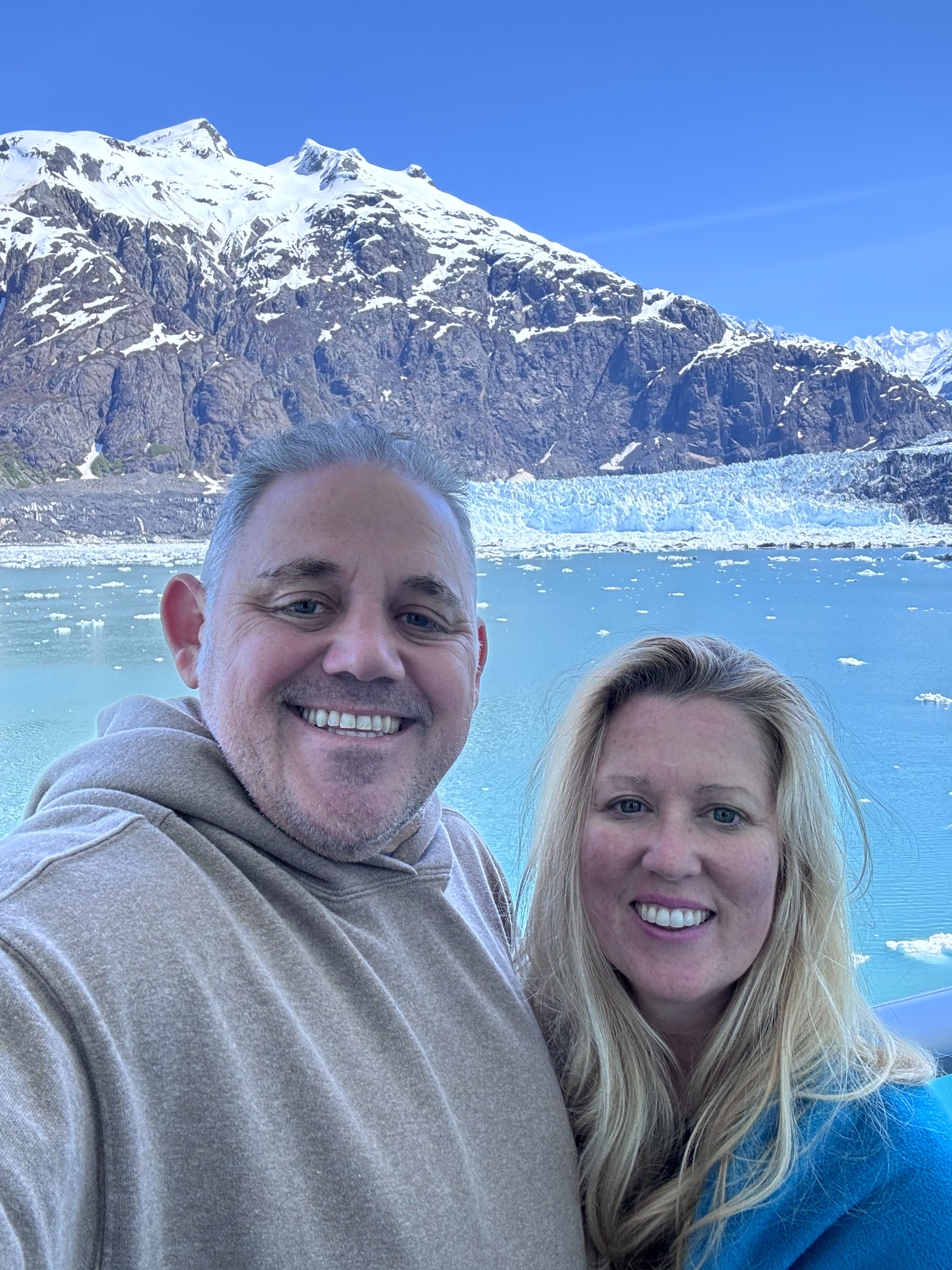 Jayson and Lori smiling with an Alaskan glacier behind them